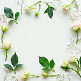 Fototapeta Kwiaty - Assorted roses heads on white background. Flowers and leaves scattered on a table, overhead view wallpaper. Flat lay, top view. Nice border.