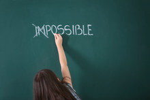 Little Girl Transforming Word Impossible  Into Possible On Chalkboard