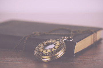 Pocket watch and book against a rustic background Vintage Retro