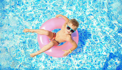 Canvas Print - little boy with pink rubber ring in swimming pool