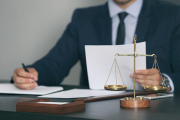 Wall Mural - Scales of justice and businessman sitting at table