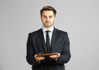 Sticker - Young handsome man with judge gavel on gray background