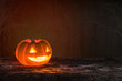 Happy halloween funny pumpkin Jack O'Lantern smiling face on grunge wood bokeh night dark background: Scary cute squash with candle light lit inside: Autumn holiday celebration festival decoration