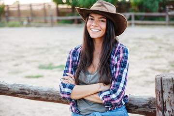 Wall Mural - Cheerful attractive young woman cowgirl standing with arms crossed