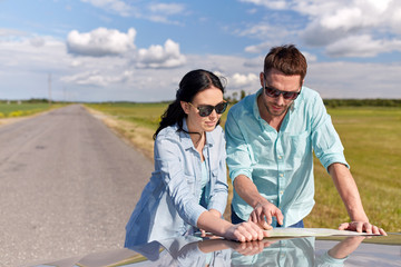 Wall Mural - happy man and woman with road map on car hood