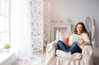 © Loginova - Technology and coziness. Beautiful young woman with cup of tea using tablet computer while sitting on armchair at home.