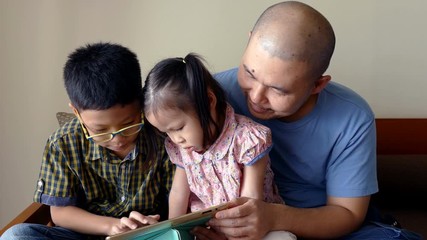 Wall Mural - Happy asian family, Father and his children looking on tablet screen