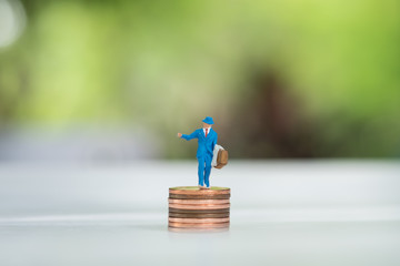 Miniature people on coins with motion of fallen coin as backgrou