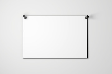 Blank white poster pinned to a plain wall with pushpins