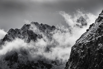 Wall Mural - black and white photo of snow covered rocky mountain peaks with fog