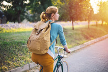 Young Woman With Backpack Cycling In The Park