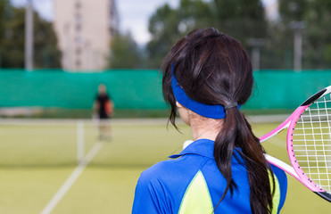 Wall Mural - Backside view of woman with tennis racket on her shoulder at the