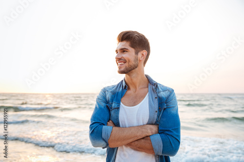 Photographie Cheerful young man standing with hands crossed on the beach