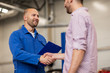 © Syda Productions - auto mechanic and man shaking hands at car shop