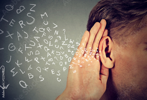 Fotografía man holds hand near ear listens carefully alphabet letters flying in