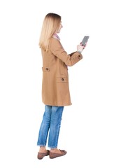 Wall Mural - back view of standing young beautiful  girl with tablet computer in the hands of. girl  watching. Rear view people collection.  backside view of person.  Isolated over white background.