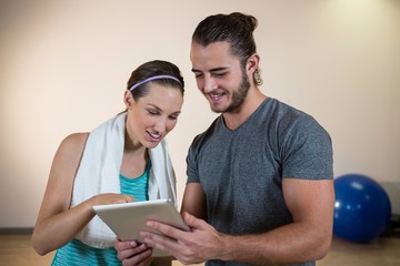 Wall Mural - Smiling fitness trainer and woman using digital tablet