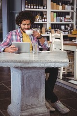 Poster - Man having coffee while looking at digital tablet
