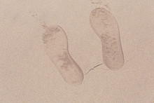 Footprints In Wet Sand Of Beach.