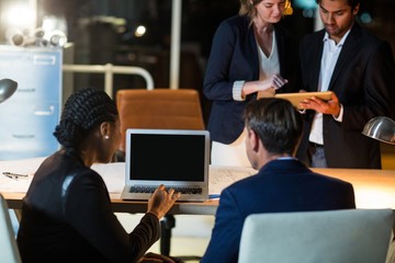 Canvas Print - Businesspeople discussing over laptop and digital tablet