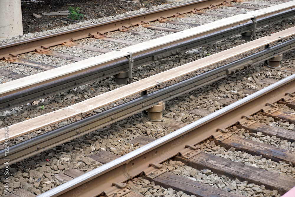 An overhead photo of the dangerous high voltage electrified third rail along railroad train tracks which powers the engine of commuter trains