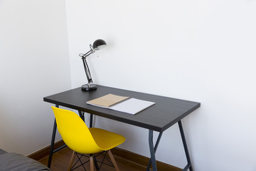 work table with book, lamp and yellow chair at home

