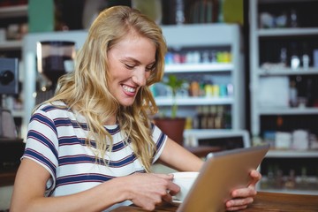 Poster - Woman using digital tablet while having cup of coffee