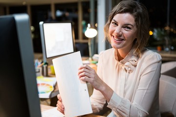 Canvas Print - Portrait of businesswoman holding document at her desk