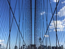 The Symmetry Of Brooklyn Bridge Cable And Buildings With Blue Sky, New York