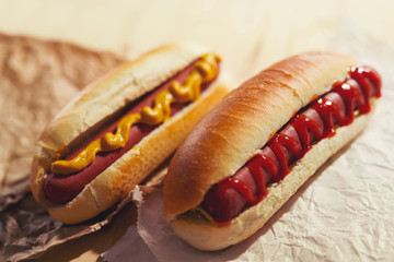 Tasty hot dogs on paper on wooden background