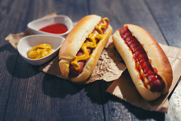 Tasty hot dogs on paper on wooden background