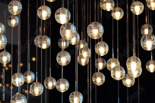 Fotomural lighting balls on the chandelier in the lamplight, light bulbs hanging from the ceiling, lamps on the dark background, selective focus, horizontal