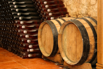 Poster - Wooden barrels and bottles with wine  in cellar