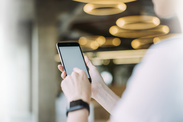 Poster - Mock up.Close-up smartphone with blank screen in female hands.View from behind,girl using gadget.Young woman pressing finger on smartphone screen,on wrist smartwatch.Blurred foreground and background.