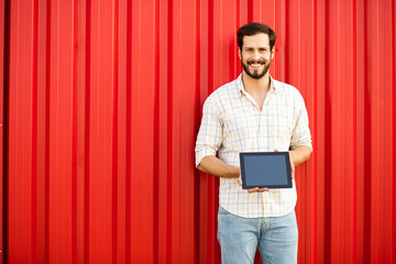 Wall Mural - handsome man presenting tablet on red background