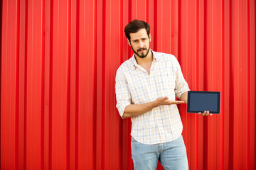 Wall Mural - handsome man presenting tablet on red background