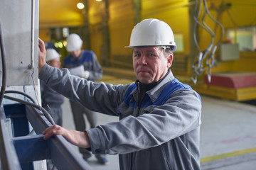 Wall Mural - A man in overalls and a helmet stands near a kiln and holding a brick