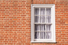 Victorian Wooden Frame White Sash Window With Glass Panels On A Red Brick Wall