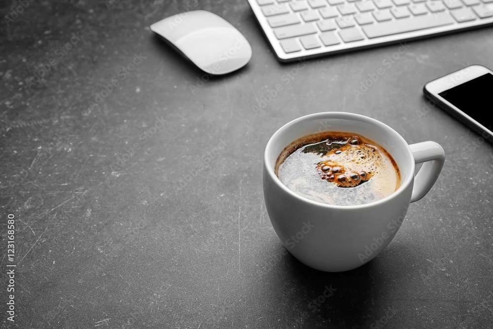 Cup of coffee with office tools on gray background