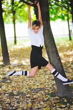 Attractive Young Woman Hanging On A Tree Branch And Smiling, Waving Legs