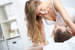 © pressmaster - A young woman over her husband in bed looking at him and smiling