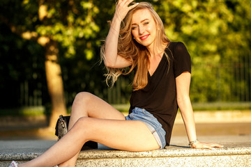 Pleasing young woman adjusts her hair while enjoying light of mo