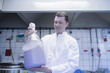 © Connect Images - Scientist carrying large bottle of chemical in laboratory