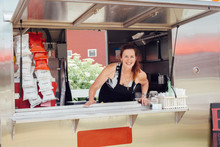 Portrait Of Woman Leaning Forward At Hatch Of Food Stall Trailer