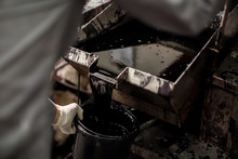 Cropped View Of Mid Adult Man Pouring Tar Into Bucket