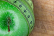 Manzana verde con cinta sobre una mesa de madera rustica (salud y concepto de dieta) 