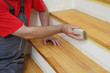 © sima - Worker sanding plank at stairs using sand paper, home renovation