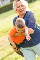 Wall Mural - Portrait of happy grandmother with grandson playing outdoor