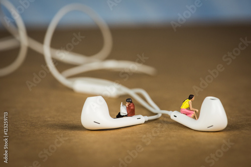 Fotografie, Obraz Miniature Figures Sitting on Earbuds listening to Music