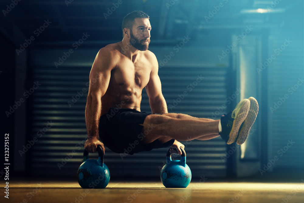 Young man is training by kettlebell. - obrazy, fototapety, plakaty 